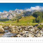 8 2027. Ein Kalender zeigt ein Gebirgspanorama mit grünem Tal, Bäumen, Felsen und einem klaren Bach unter einem blauen Himmel.