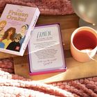 "Das Frauen Orakel", Kartentext über Frauen, die die Welt prägen. Neben einer Tasse und einer weichen Decke platziert.