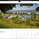 August, Kalenderansicht. Darunter Landschaft mit Gebäuden, Bäumen und See im Hintergrund.