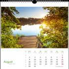 Kalenderblatt für August. Oben eine ruhige See mit hölzernem Steg umgeben von grünen Bäumen im Sonnenlicht.