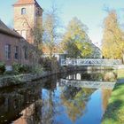 Stepenitz-Brücke zum Hagen. Backsteingebäude, Brücke über ruhigen Fluss, herbstliche Bäume spiegeln sich im Wasser.