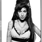 Eine Frau mit hochtoupierter Frisur, einer Halskette und Tattoos, darunter die Worte "Blake" und "Cynthia".