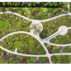 214 links, 215 rechts unten. Luftaufnahme eines Gartens mit geschwungenen Wegen und bunten Pflanzflächen.