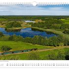 August, Lößnitzgrundbahn am Dippelsdorfer Teich bei Moritzburg. Eine Eisenbahn fährt durch eine grüne, seenreiche Landschaft.
