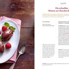 "Die schnellste Mousse au Chocolat der Welt." Zwei Schokoladen-Nocken, Himbeeren, Minzblätter, Löffel, rosa Serviette.