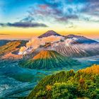 Ich kann keine Texte im Bild sehen. Zu sehen ist eine malerische Vulkanlandschaft bei Sonnenaufgang, umgeben von dichten Wolken.