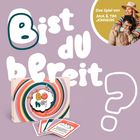 Text: "Bist du bereit? Das Spiel von Ana & Tim Johnson." Eine Spielbox mit buntem Design und mehreren Karten.
