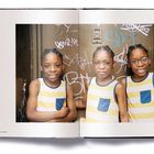 Graffitis: "sin", "2012". Drei Kinder in gestreiften Shirts, fröhlich.