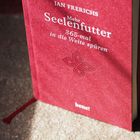 Das Cover zeigt den Titel "Mehr Seelenfutter: 365-mal in die Weite spüren" von Jan Frerichs auf einem roten Buch.