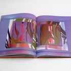 Ein aufgeschlagenes Buch zeigt abstrakte Kunst mit intensiven Farben auf zwei Seiten in lila und pink Tönen.