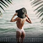 Kalender mit August-Daten. Eine Frau im Badeanzug am Wasser, mit Hut, umgeben von Palmenblättern.