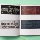 Texte: „dass man mit Touristen Geld machen kann“, „Schweigen“, „Raub“, „Arbeit“. Vier Tafeln auf einer Doppelseite.