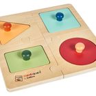 „Montessori by Eichhorn“ auf einer Holzpuzzle-Tafel mit vier bunten Formen: Dreieck, Kreis und zwei Quadrate.