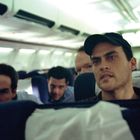 Männer in einem Flugzeugsitz, konzentriert und angespannt. Die Kabine ist leicht beleuchtet.