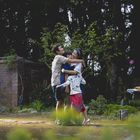 Eine Gruppe von vier Personen umarmt sich draußen in einem grünen Garten. Sie wirken glücklich und verbunden.