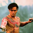 Ich kenne keine Texte hier. Ein muskulöser Mann mit Tattoos hält ein Messer. Er wirkt entschlossen und kämpferisch.