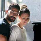 Ein Mann und eine Frau stehen zusammen in einem hellen Raum, sie lächeln leicht und eine grüne Landschaft ist im Hintergrund.