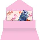 Eine pinke Karte mit Bonbon-Muster in einem Umschlag, darin ein gefalteter 20-Euro-Schein.