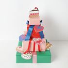 Bunte Geschenke mit Herz- und Kuchen-Illustrationen, verziert mit roten und blauen Bändern in einem Stapel arrangiert.