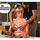 "Die liebestollen Baronessen" in einer Sprechblase; eine Frau in rosa-weißem Kleid wird von einem Mann umarmt.