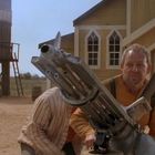 Der Text "WATER" steht auf einem Wasserturm. Zwei Männer mit einer Gatling-Gun vor einem gelben Holzgebäude.