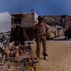 "New Orleans" ist auf einem Gebäude zu sehen. Ein Mann steht neben einem Planwagen und ein anderer liegt auf einer Trage.