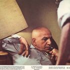 "MGM Presentation 'CLAY PIGEON' Metrecolor." Ein Mann liegt mit einer Pistole am Kopf, während eine Lampe den Raum beleuchtet.