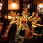 Schild mit "Keine Haftung". Gruppe fröhlicher Menschen, die an einem Tisch zusammen anstoßen, warme, gesellige Atmosphäre.