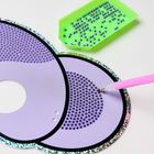 Lila Papierform mit Glitzerkante, grüne Schale mit Perlen, pinker Stift, perforierte Muster passend darauf.