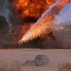 Kein Text erkennbar. Eine Explosion, Flammen und Rauch in einer Wüstenlandschaft, mit einer Person am Boden.