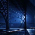 Blaue Straßen- und Brückenszene bei Nacht, schwaches Licht von Autos und Laternen. Mysteriöse Atmosphäre.