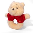 Ein weicher, beige-gelber, runder Teddybär mit rotem T-Shirt und kleinem Logo darauf.