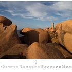 Côte de Granit Rose, September Kalenderblatt. Große rötliche Granitfelsen, ein Leuchtturm im Hintergrund, blauer Himmel.