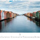 Kalendermonat September. Bunte Lagerhäuser an einem Fluss in Trondheim, blauer Himmel mit Wolken.