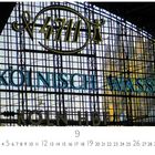 „4711“ und „Kölnisch Wasser“ sind groß auf einem Glasdach zu sehen. Darunter „Hauptbahnhof“ und ein Kalender.