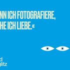 „WENN ICH FOTOGRAFIERE, MACHE ICH LIEBE.“ Alfred Stieglitz. Zwei stilisierte Augen auf blauem Hintergrund.