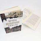 „Wien Berlin - Wo die Moderne erfunden wurde“. Ein Buch zeigt historische Stadtansichten auf dem Cover, daneben ein offenes Buch.