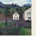 Annaberg-Buchholz, Häuser vor Hügeln mit Bäumen und einem Zaun im Vordergrund, Landschaft mit kleinem Garten.