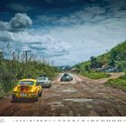 Porsche 911 Safari, Porsche Cayenne, Porsche 953 Dakar. Autos auf schlammiger Straße in ländlicher Umgebung.