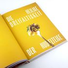 Text: "Die heilige Dreifaltigkeit der Nudelteige". Ein goldener Löffel hält Pasta, vor gelbem Hintergrund.
