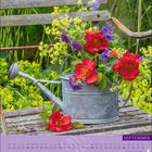 Der Kalender zeigt den Monat "SEPTEMBER". Eine Gießkanne mit roten, violetten und gelben Blumen steht auf einer Holzbank.