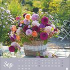 "Sep" und Kalendertage in einem lila Kasten. Blumenkorb mit bunten Blumen auf einem Tisch im Garten.