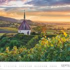 SEPTEMBER. Landschaft mit Weinbergen, kleinem Turm, Hügeln und stimmungsvollem Sonnenuntergang im Hintergrund.