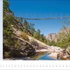 Text: "Auf dem Grande Randonnée 20... Frankreich, Mittelmeer, Korsika..."
Beschreibung: Hängebrücke über felsige Landschaft mit Bäumen, blauer Himmel.