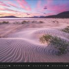 09; wellenförmiger Sand mit Pflanzen, im Hintergrund Hügel und ein Himmel in Rosa- und Blautönen.