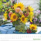 Kalenderblatt "September" mit einem Blumenarrangement aus Sonnenblumen und verschiedenen Beeren auf einem Tisch.