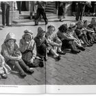 "D’r Zoch kött – aber wann? Kinder warten vor dem Alten Rathaus auf den Rosenmontagszug." Kinder in traditionellen Kostümen sitzen.