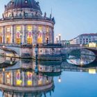 Text: "Central Berlin Highlights". Bild einer beleuchteten Kuppel mit Brücke, reflektiert im Wasser.