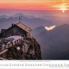 Kalender mit September-Daten und Alpenhütte im Sonnenuntergang auf einem Berggipfel über einer Talebene mit See.