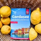 Reiseführer "Gardasee mit Verona und Brescia" mit Zitronen in einem Korb arrangiert.